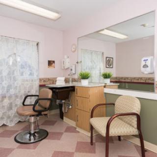 A cozy interior of a salon featuring a waiting area with stylish chairs and a large mirror.