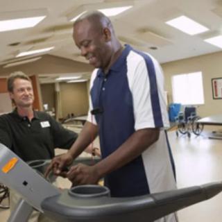 A man undergoing rehabilitation exercises on a treadmill under the supervision of a therapist.