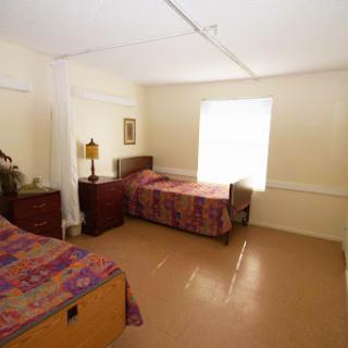 A cozy bedroom featuring two beds with colorful bedding and natural light streaming through the window.