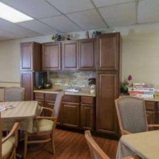 A cozy kitchen area featuring wooden cabinets, tables, and chairs.