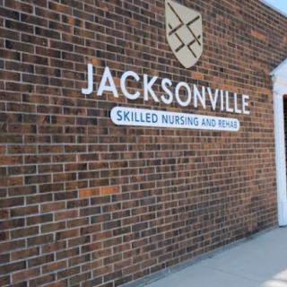 The exterior sign of Jacksonville Skilled Nursing and Rehab on a brick wall.