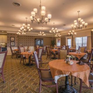 An elegant dining room with tables, chairs, and chandeliers.