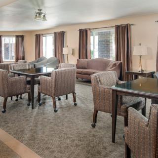 A spacious living room with multiple tables and chairs, featuring comfortable couches and curtains.