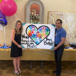 A joyful moment captured as a couple showcases their colorful artwork at a celebration.