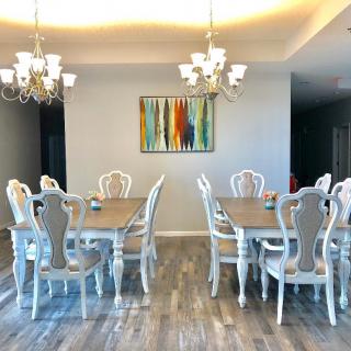 Elegant dining room with vintage-style furniture and chandeliers, featuring wood flooring and abstract wall art.