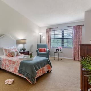 A cozy bedroom with a single bed, armchair, and decorative elements.