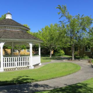 A serene park with a gazebo and winding pathways under a clear blue sky.