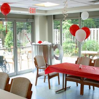A room decorated for a celebration with red and white balloons and a table with a red tablecloth.