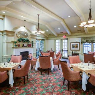 An elegant dining room with well-arranged tables and comfortable seating, featuring chandeliers and tasteful decor.