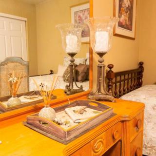 A cozy bedroom featuring a wooden dresser with decorative candles and a mirror.