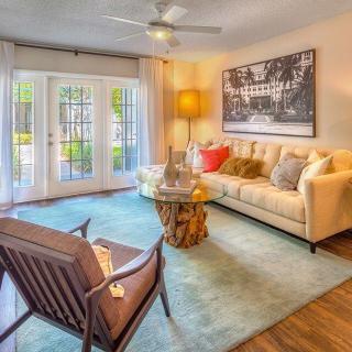 A cozy living room with a comfortable sofa, armchair, and stylish coffee table, complemented by modern artwork and large glass doors.