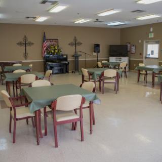 A spacious community dining hall with neatly arranged tables and chairs.