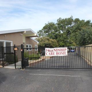 Entrance gate of a care home with surrounding trees and building.
