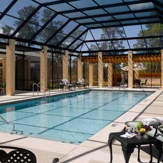 An elegant indoor swimming pool with a glass roof and seating area.