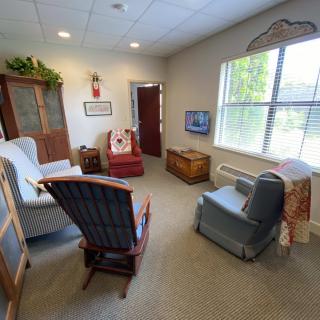 A cozy living room with various armchairs, a large window, and homey decor.