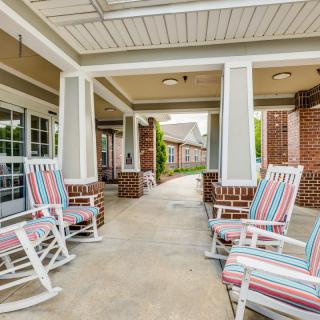 A covered patio with striped-cushion rocking chairs provides a cozy outdoor seating area.
