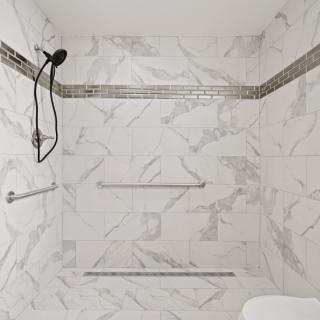 A modern shower space with white tiled walls and a sleek design.