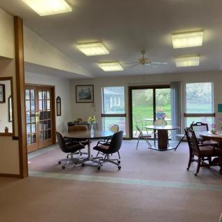 A spacious meeting room with tables and chairs, featuring large windows that let in natural light.