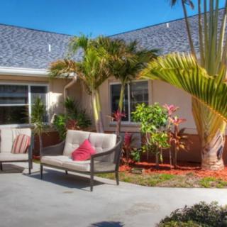 A cozy outdoor patio with comfortable seating surrounded by lush greenery and palm trees.