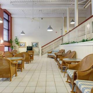 A spacious lobby area with wicker chairs, small tables, and indoor plants.