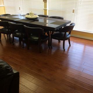 A dining room with a large table and chairs on a hardwood floor.