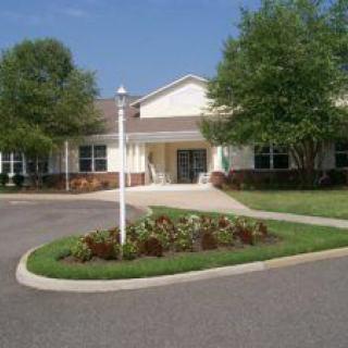 A single-story building with a landscaped circular driveway and trees.