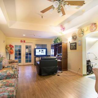 A cozy living room with a ceiling fan, television, and decorated walls.