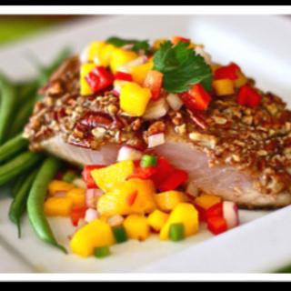 A beautifully plated salmon dish topped with mango salsa, served alongside green beans.
