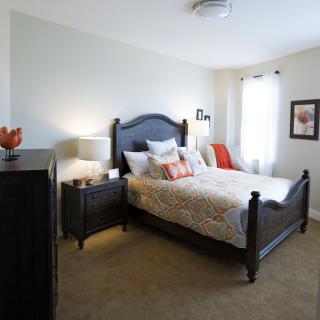 A cozy bedroom with a dark wooden bed, soft bedding, and warm lighting.
