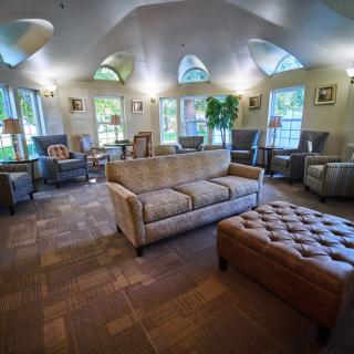 A spacious and well-furnished living room with sofas, armchairs, and large windows allowing natural light.