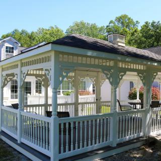 A white wooden gazebo located in a backyard setting.