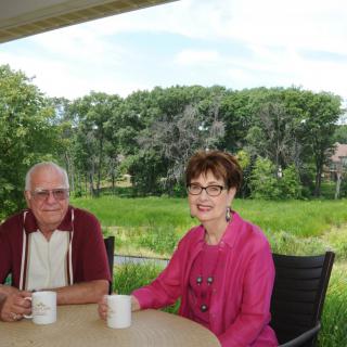 A senior couple enjoying coffee on a patio with a scenic view.