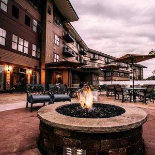 A cozy outdoor patio area with a fire pit and comfortable seating in front of an apartment building.