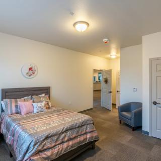 A modern bedroom with a neatly made bed and comfortable seating.