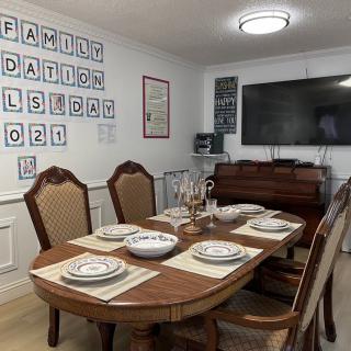 A well-decorated dining room with a table set for a meal, featuring elegant chairs and wall art.