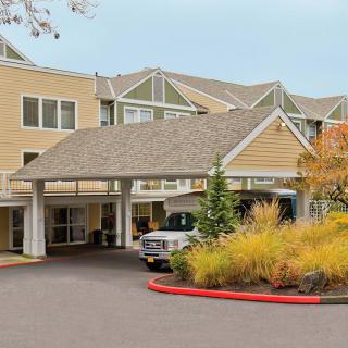 A building entrance with a driveway and landscaped surroundings.