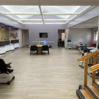 A spacious office interior featuring a central table with chairs, surrounded by bright lighting and functional furniture.