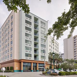 A modern apartment building in an urban setting with cars parked nearby.