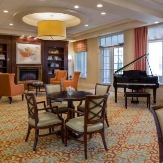 A cozy lounge with a grand piano, seating area, and fireplace.