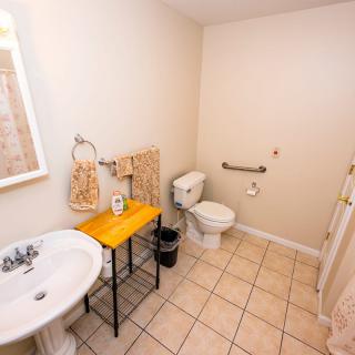 A well-organized bathroom featuring a sink, toilet, and handrail on tile flooring.