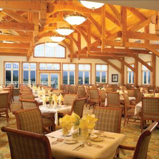 An elegant restaurant dining room with wooden beams and well-set tables.