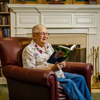An elderly man enjoys a quiet moment reading in a cozy library setting.