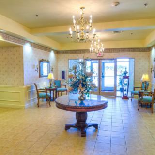 A welcoming lobby area featuring elegant chandeliers, a circular table with flowers, and comfortable seating.