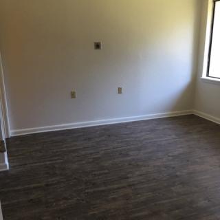 An empty room with wooden flooring and a large window.