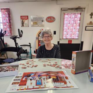 An elderly person enjoying a puzzle at a cozy indoor setting.