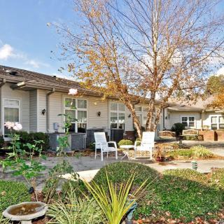 A cozy patio area with chairs surrounded by a lush garden and trees at the back of a house.