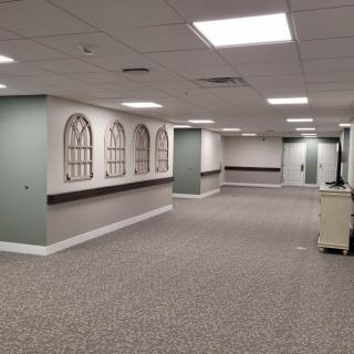 An empty office hallway with carpeted floors and ceiling lights.
