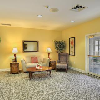 A cozy living room with yellow walls, featuring a sofa, lamps, and decorative elements.