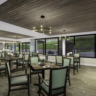 A modern restaurant dining area with neatly arranged tables and chairs, accented by stylish chandeliers and large windows.
