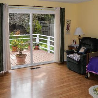 A cozy living room with wooden flooring and a sliding glass door leading to a patio adorned with potted plants.